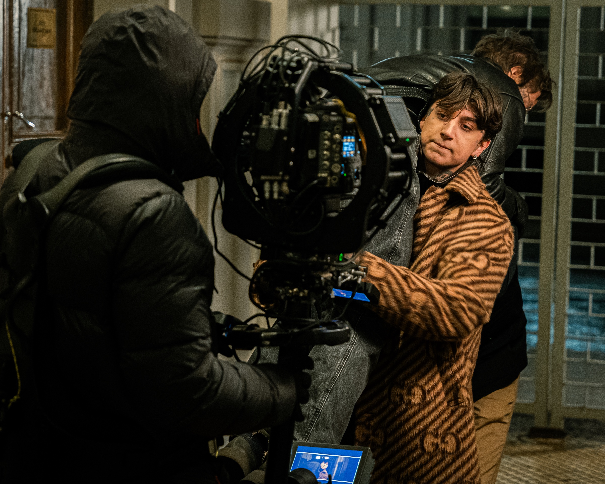 A camera operator filming a performer with crew nearby
